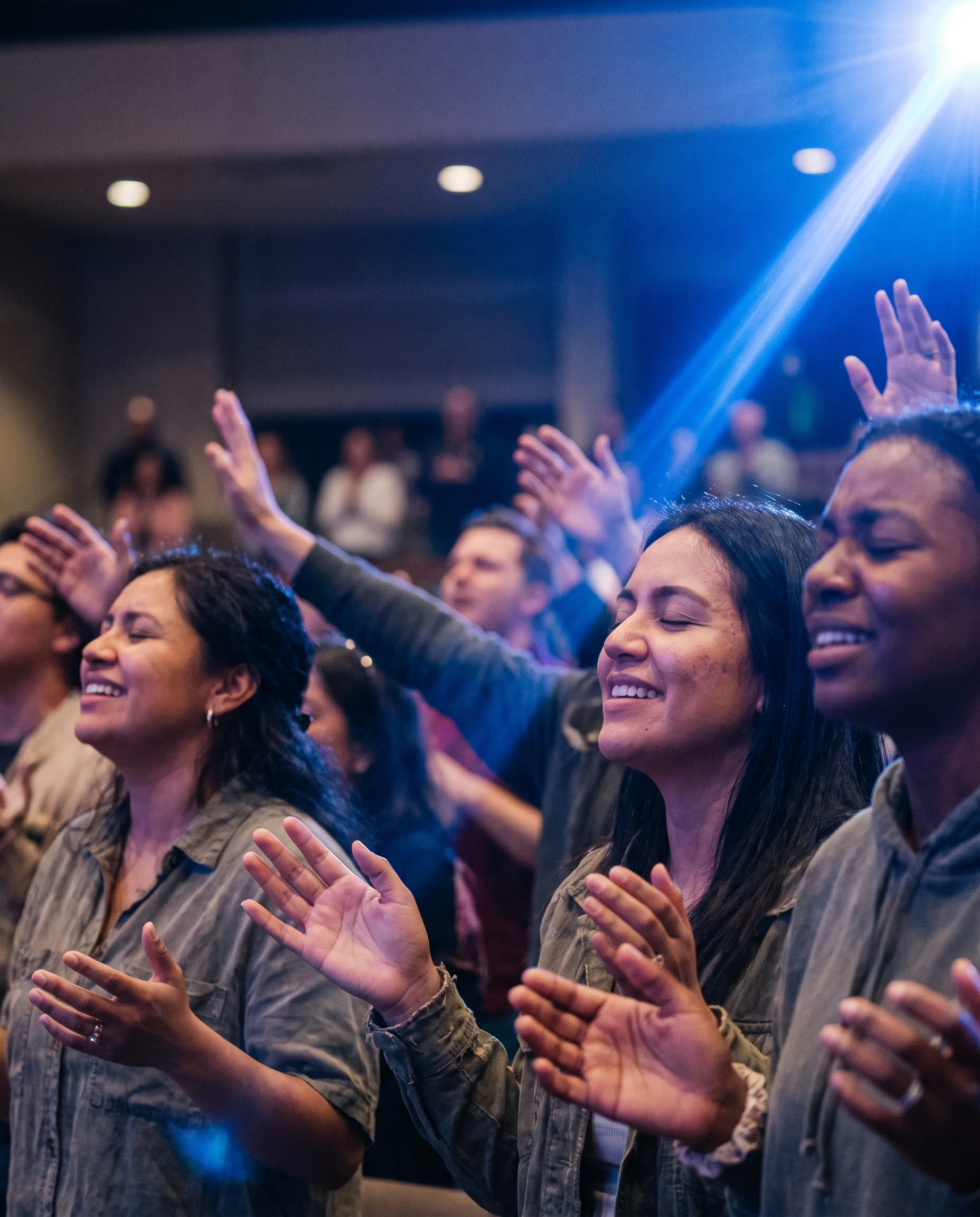 Close-up of worshippers with hands raised under blue stage light